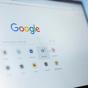 Google homepage open on a monitor with shortcut icons for Facebook, Instagram, ChatGPT, and a stock market site.