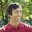 Smiling man in a red polo stands in a sunny park, thinking about web design and digital marketing strategies.