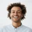Curly-haired young man smiling in a light shirt, facing forward on white background, perfect for web design or SEO services.